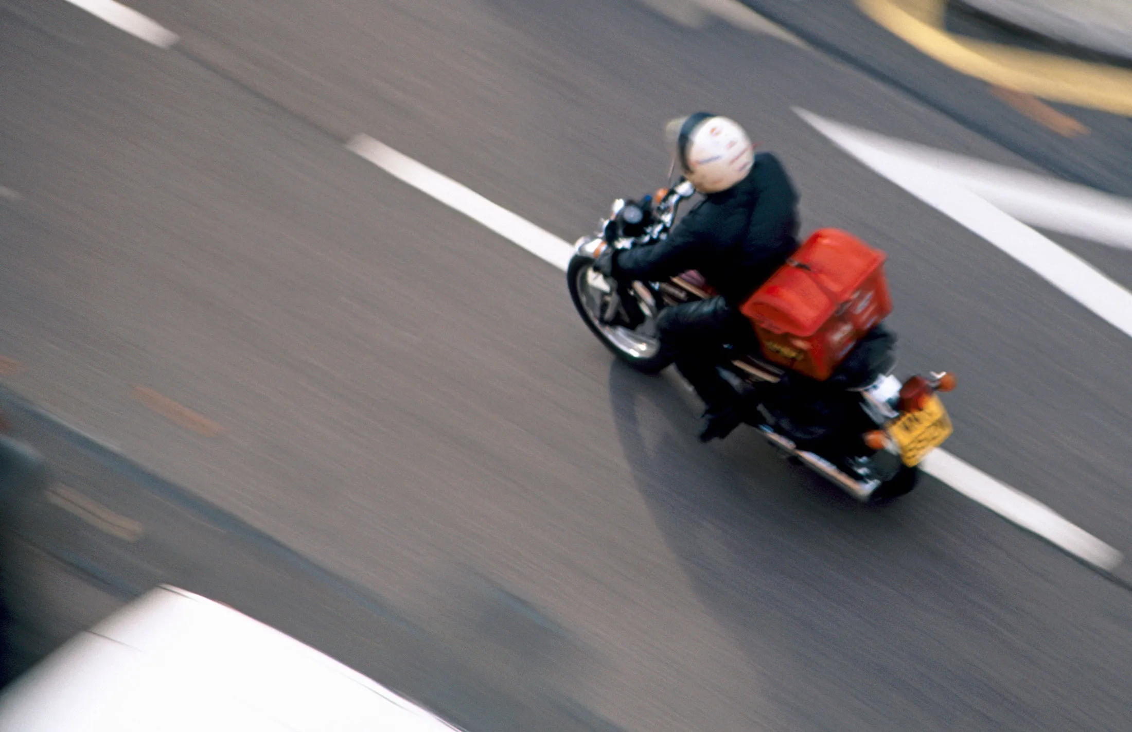 Motorcycle courier speeding along a road from above, London W14, England

