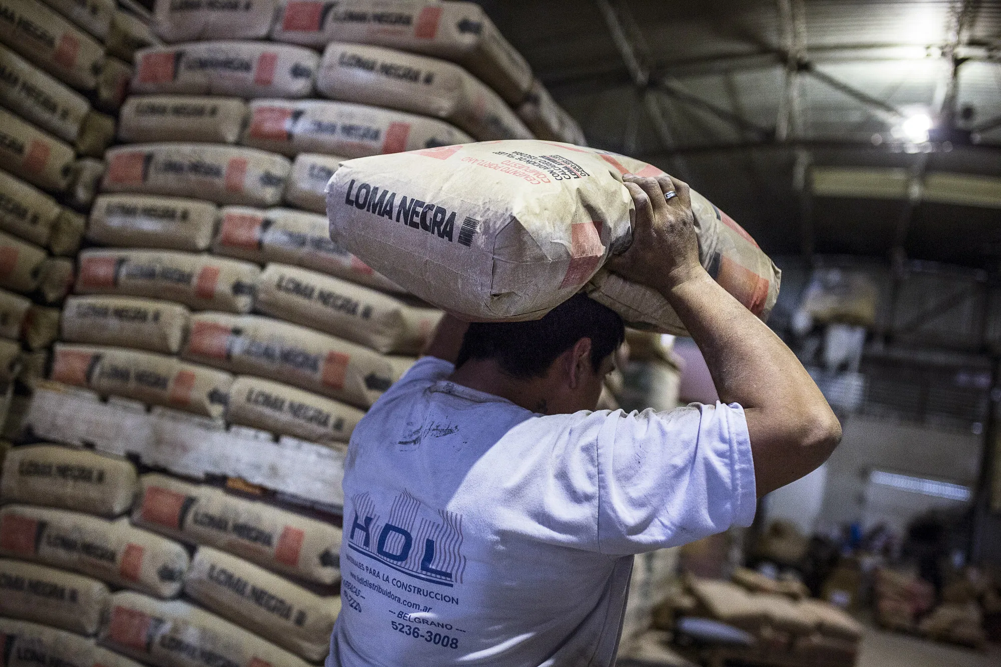 A worker carries a bag of Loma Negra Cia Industrial Argentina SA cement. Loma Negra is InterCement’s Argentina unit.