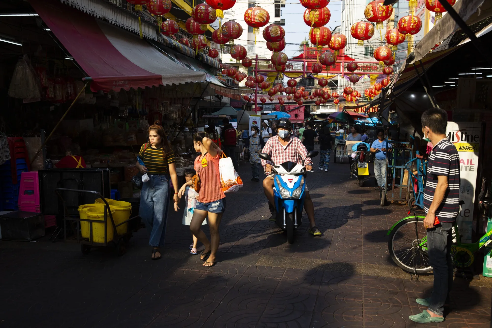 A motorcyclist wearing a protective mask travels through a market in the Chinatown district of Bangkok.