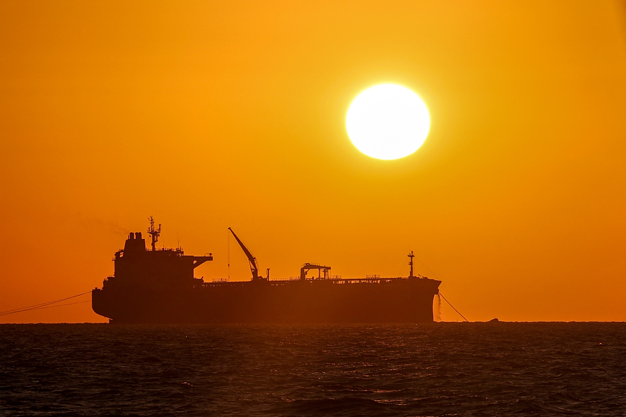 TOPSHOT - The sun sets near a cargo ship by the port of Haifa in northern Israel on October 8, 2024. (Photo by Jack GUEZ / AFP) (Photo by JACK GUEZ/AFP via Getty Images)
