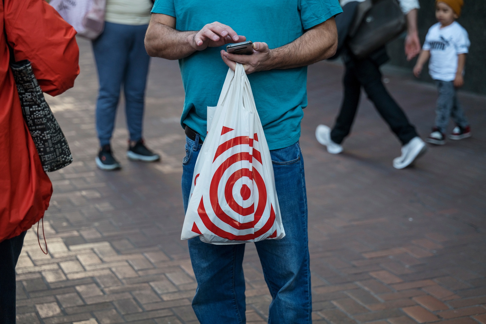 A pedestrian holding a Target Corp. shopping bag uses a mobile phone in San Francisco, California.