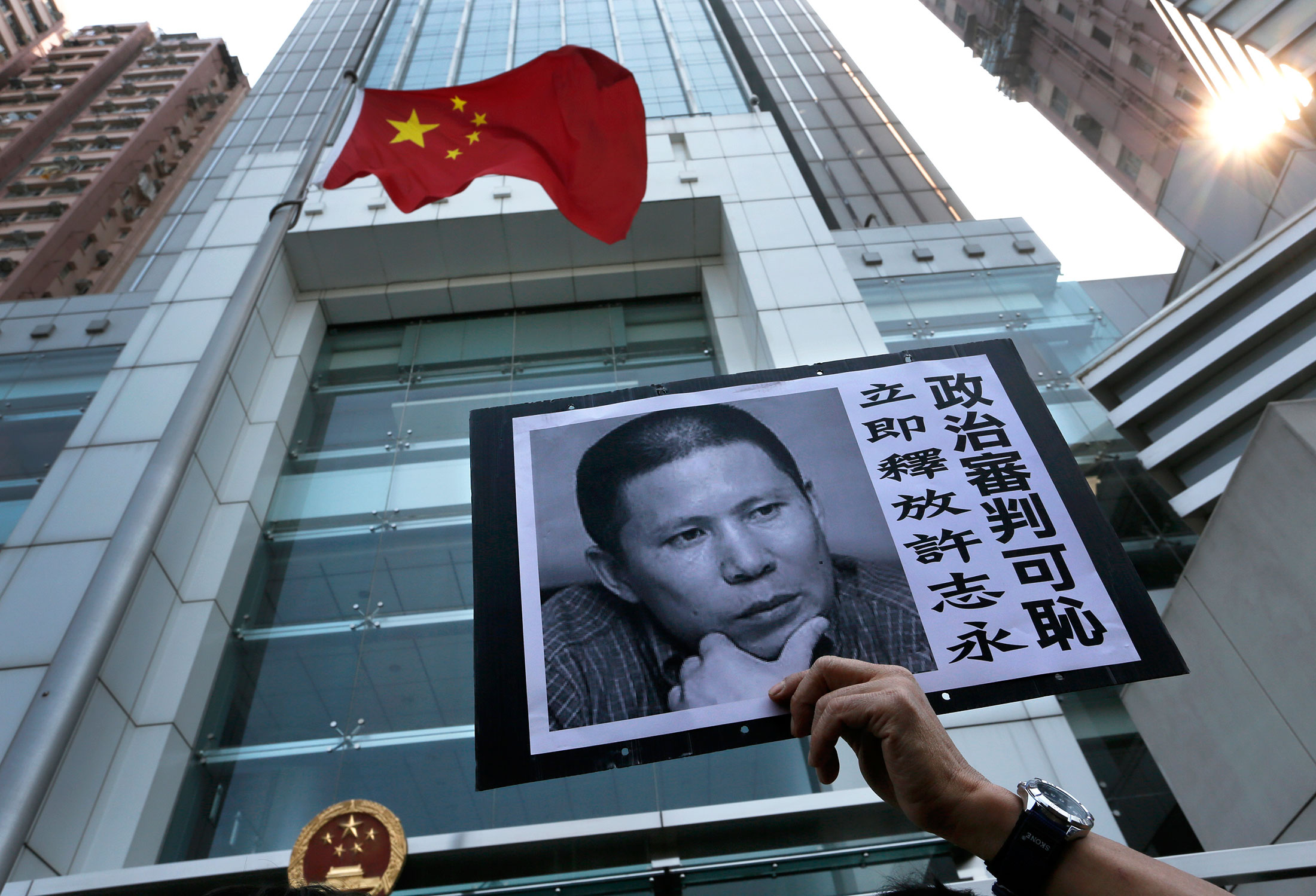 A placard with a photo of Xu Zhiyong is raised by a demonstrator outside the Chinese liaison office in Hong Kong in 2014.