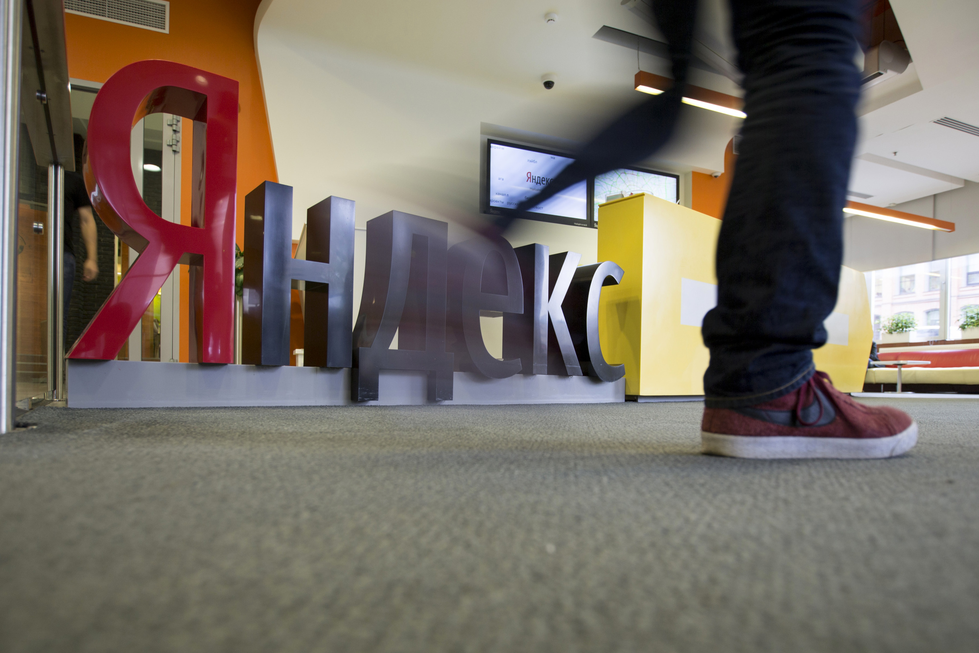 A visitor walks past a logo displayed in the reception area at the headquarters of Yandex NV in Moscow.