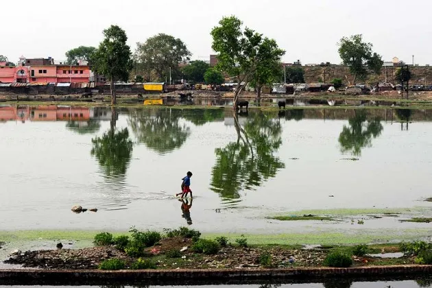 Indian children wade through a submerged area after a rain shower in Allahabad, India on June 9, 2013