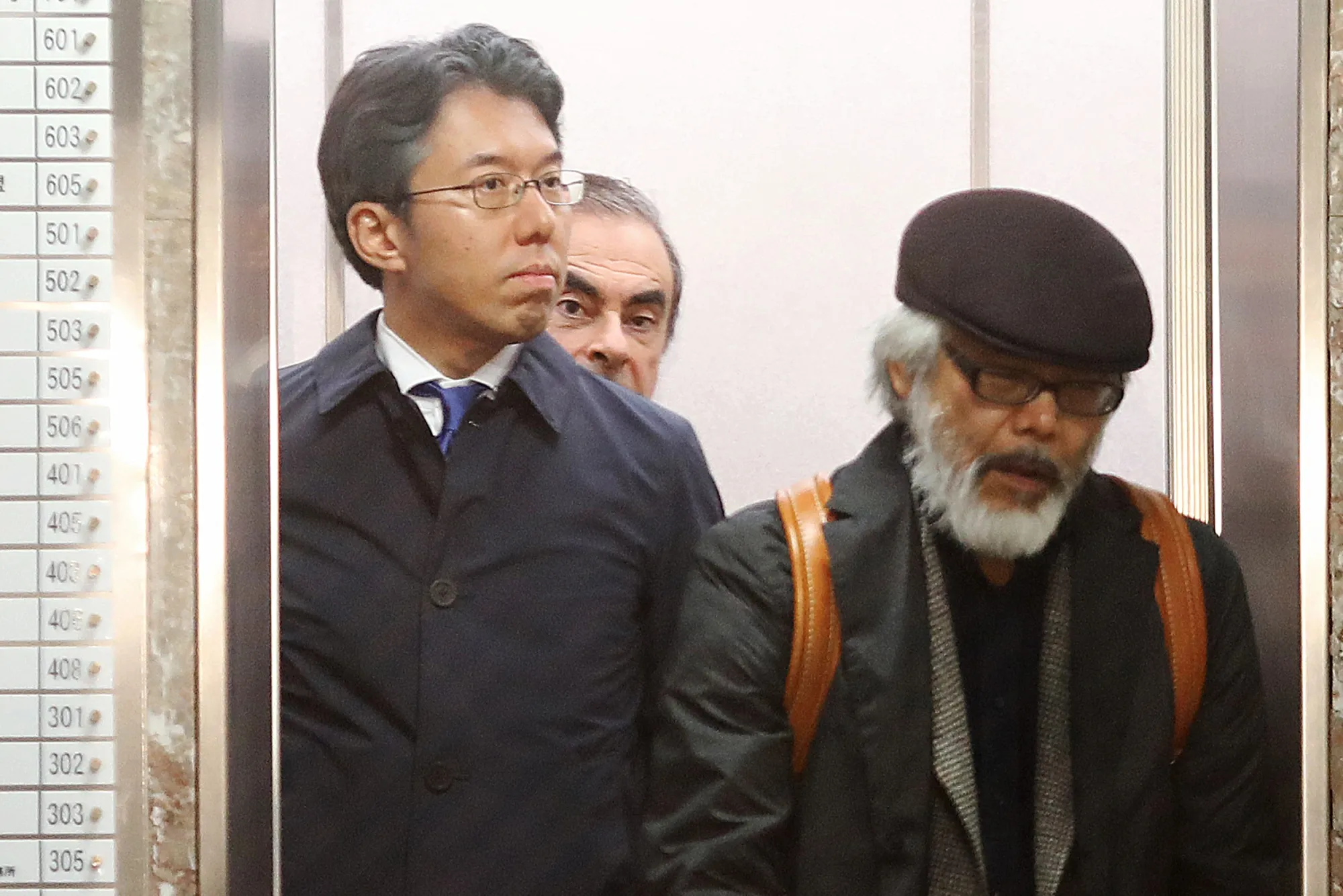 Carlos Ghosn, former chairman of Nissan Motor Co., center rear, and Takashi Takano, one of Ghosn's lawyers, right, leave Takano's office in Tokyo.