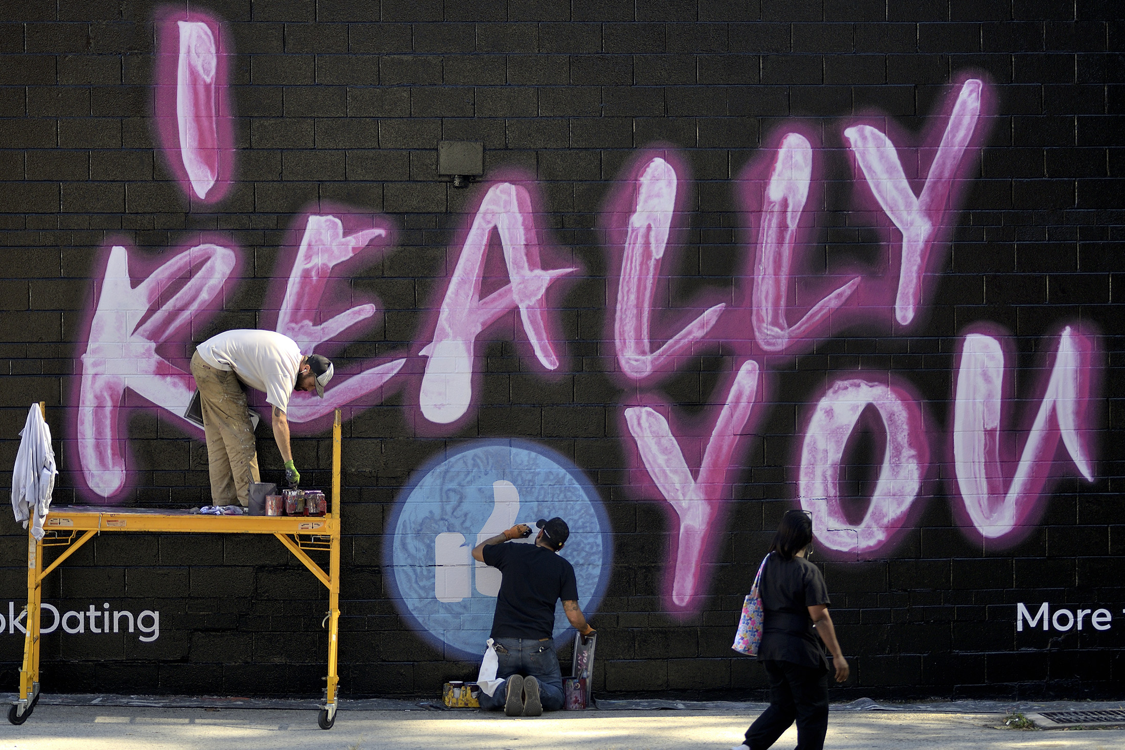 Painters work on an advertisement for the Facebook dating service in Philadelphia, U.S., in 2019. 