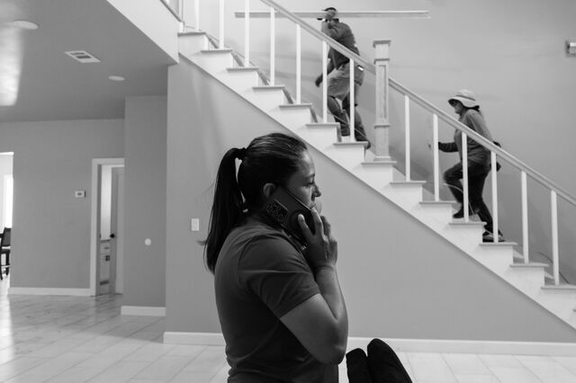  Nunez takes a phone call as a contractor finishes installing and trimming a door  at home.