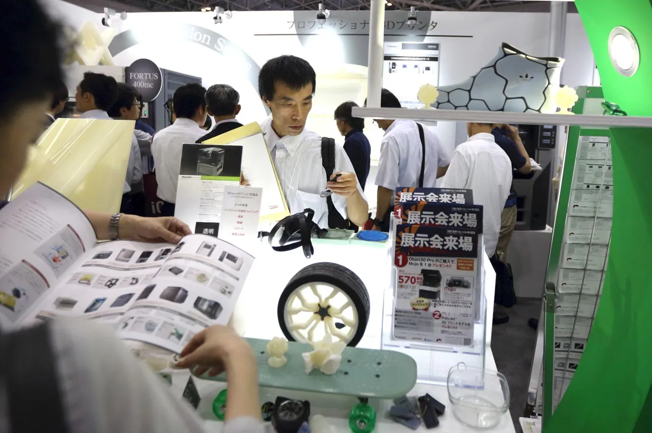 Visitors look at products made by 3-D printers displayed in the Stratasys Ltd. both at the 3D & Virtual Reality Exhibition in Tokyo, Japan, on June 21, 2013. Photographer: Tomohiro Ohsumi/Bloomberg