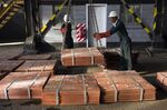 Workers load batches of copper sheets ready for shipping inside a warehouse facility&nbsp;in Mufulira, Zambia.