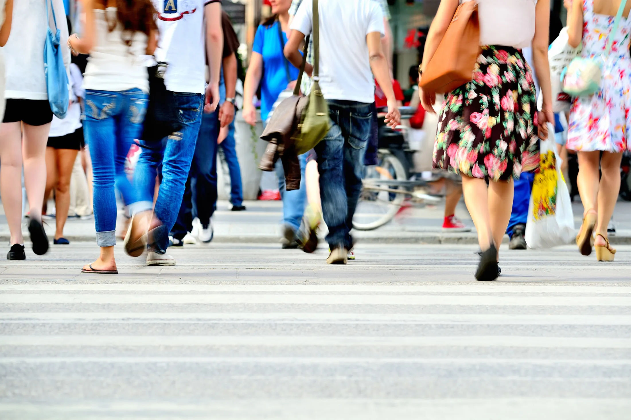 Motion blurred pedestrians crossing sunlit street
