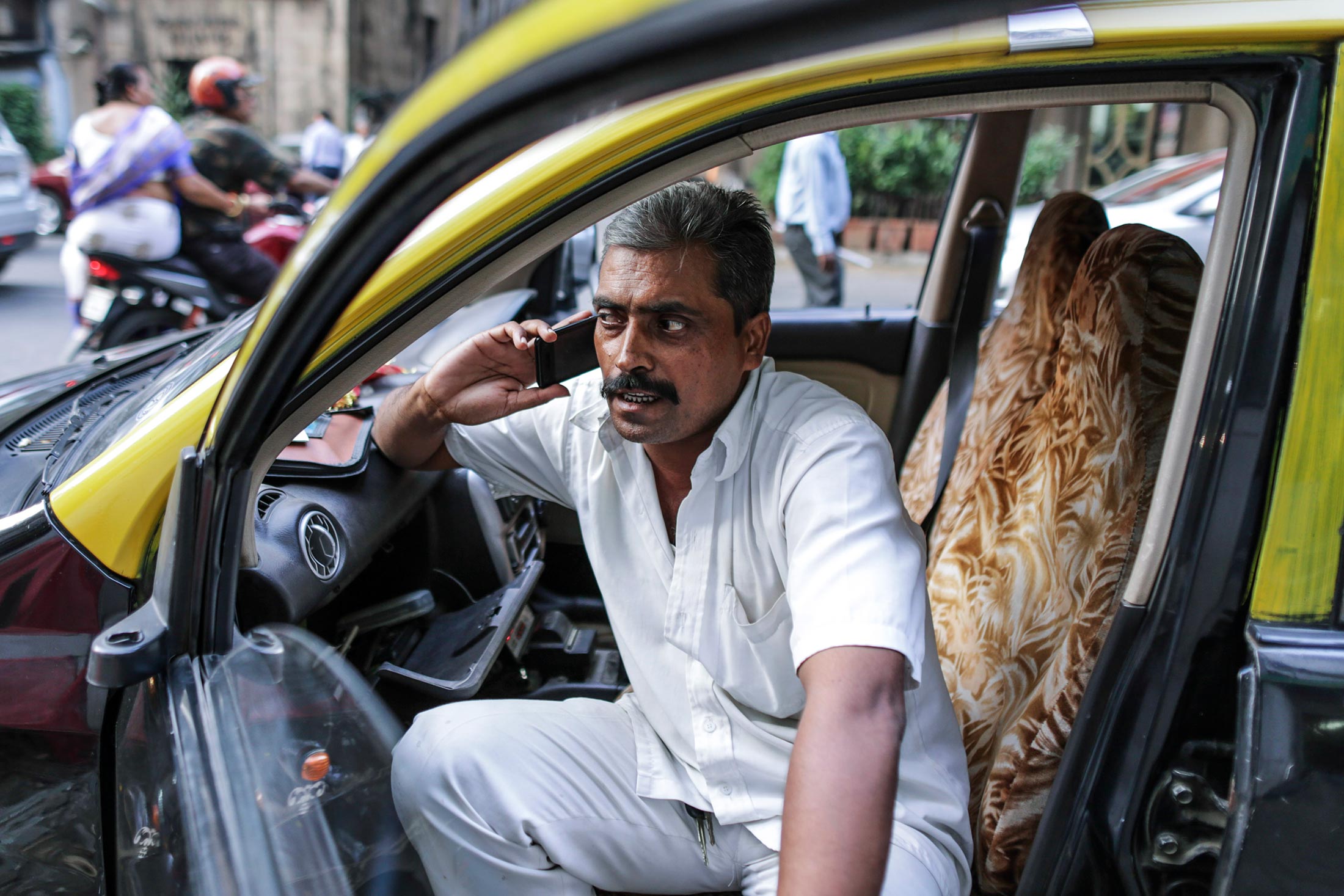 A taxi driver talks on mobile phone as sits inside his taxi in Mumbai, India, on Oct. 19.
