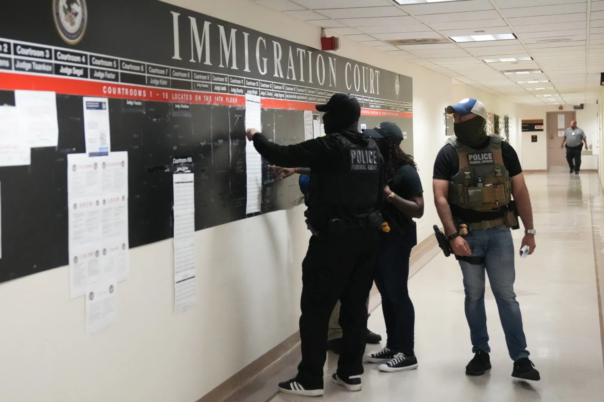 US Immigration and Customs Enforcement (ICE) agents look over lists of names and their hearing times and locations inside the Federal Plaza courthouse in New York.