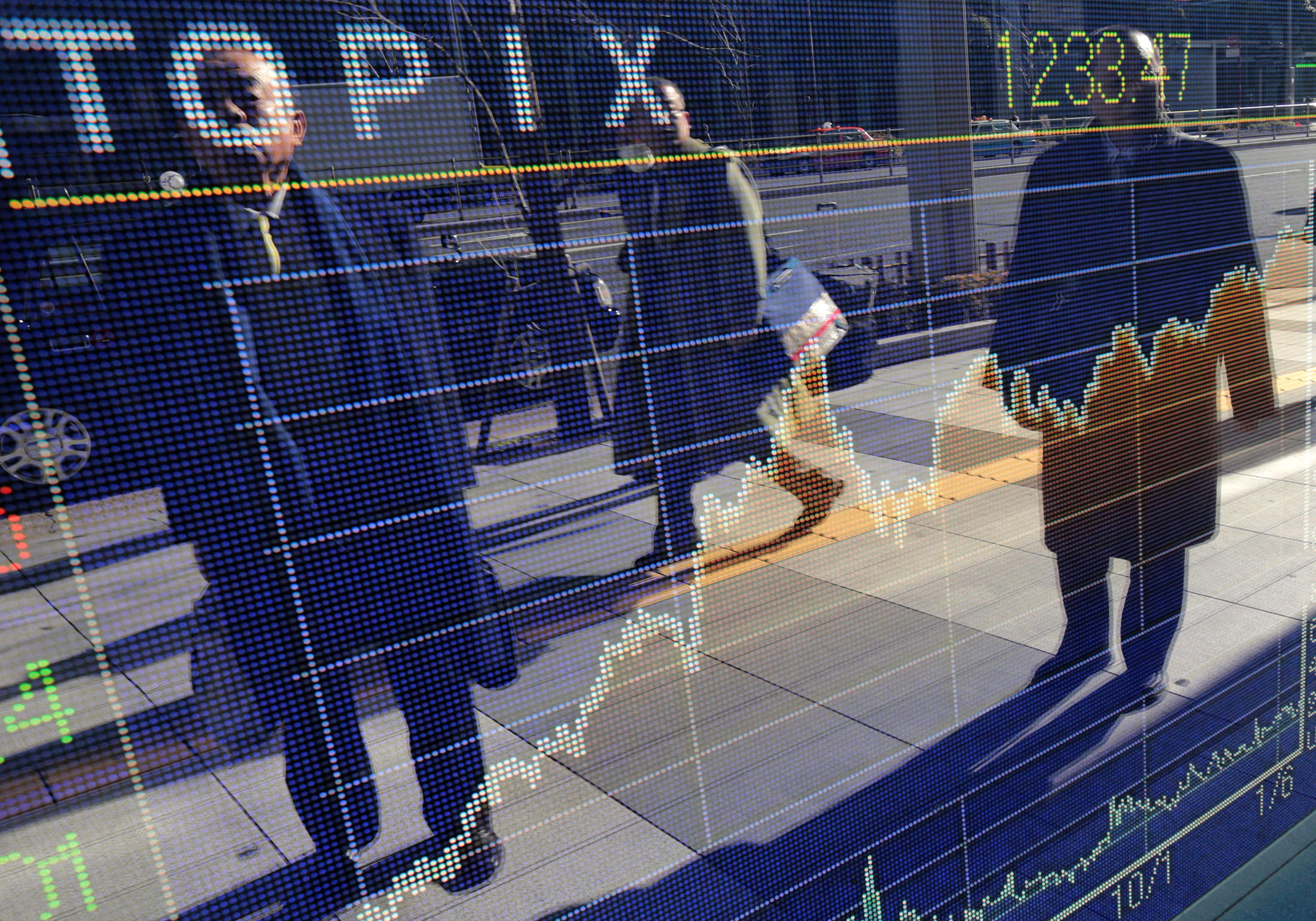People look at an electronic stock board displaying the day's movements of the Topix index outside a securities firm in Tokyo, Japan.

