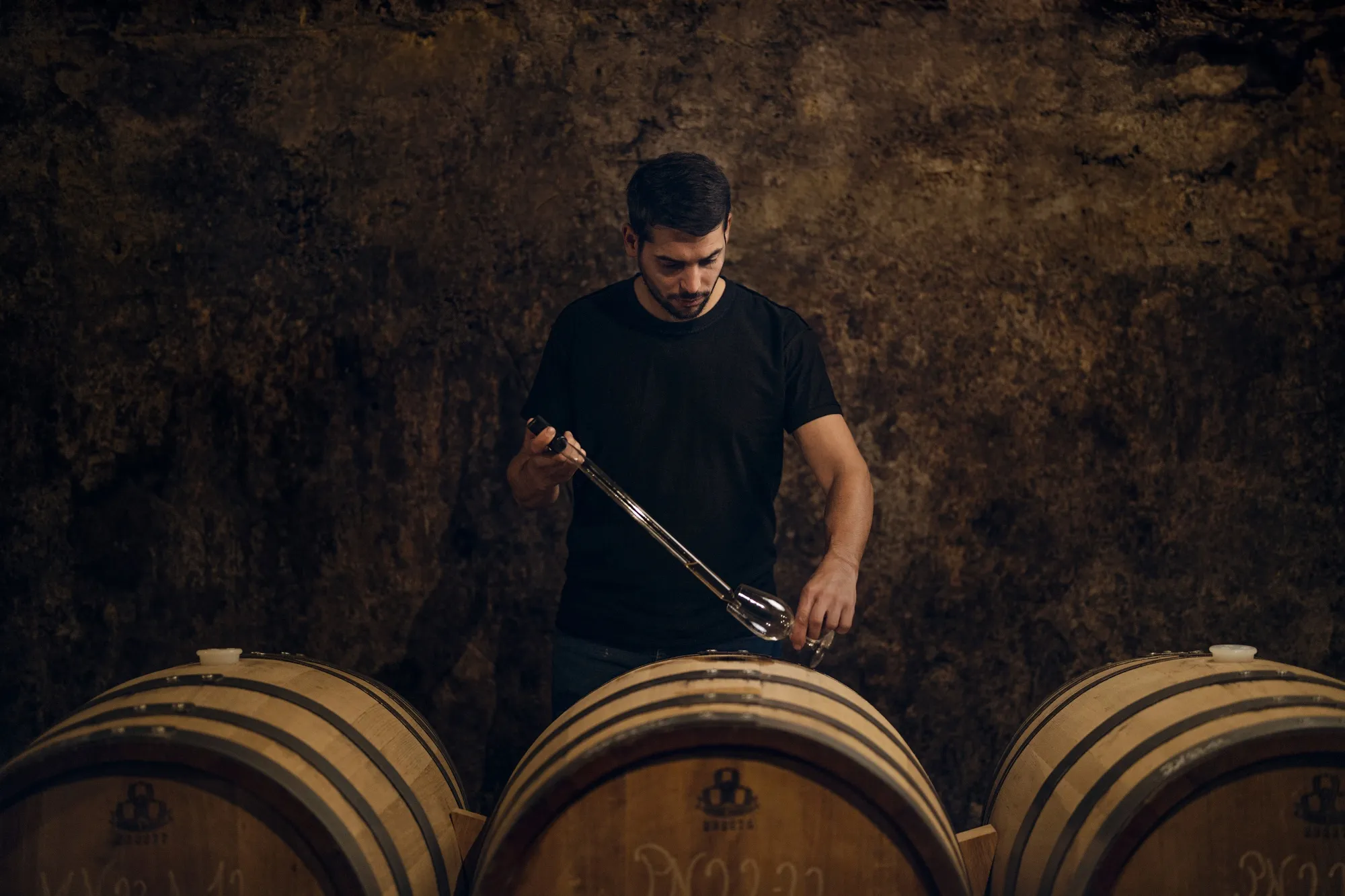 A worker takes a sample from a barrel at Champagne de Lossy.