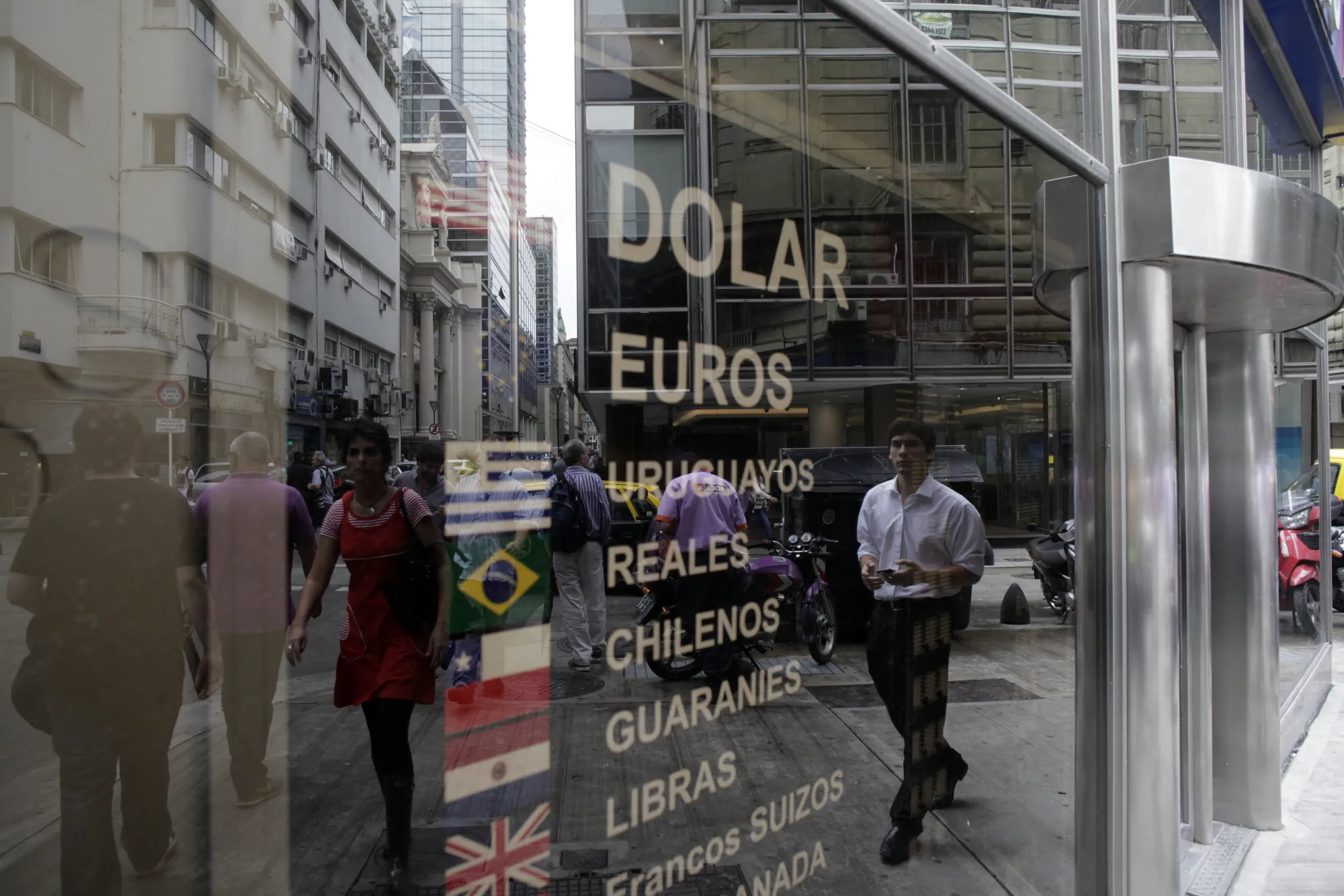 Pedestrians are reflected in the window of a currency exchange in Buenos Aires.