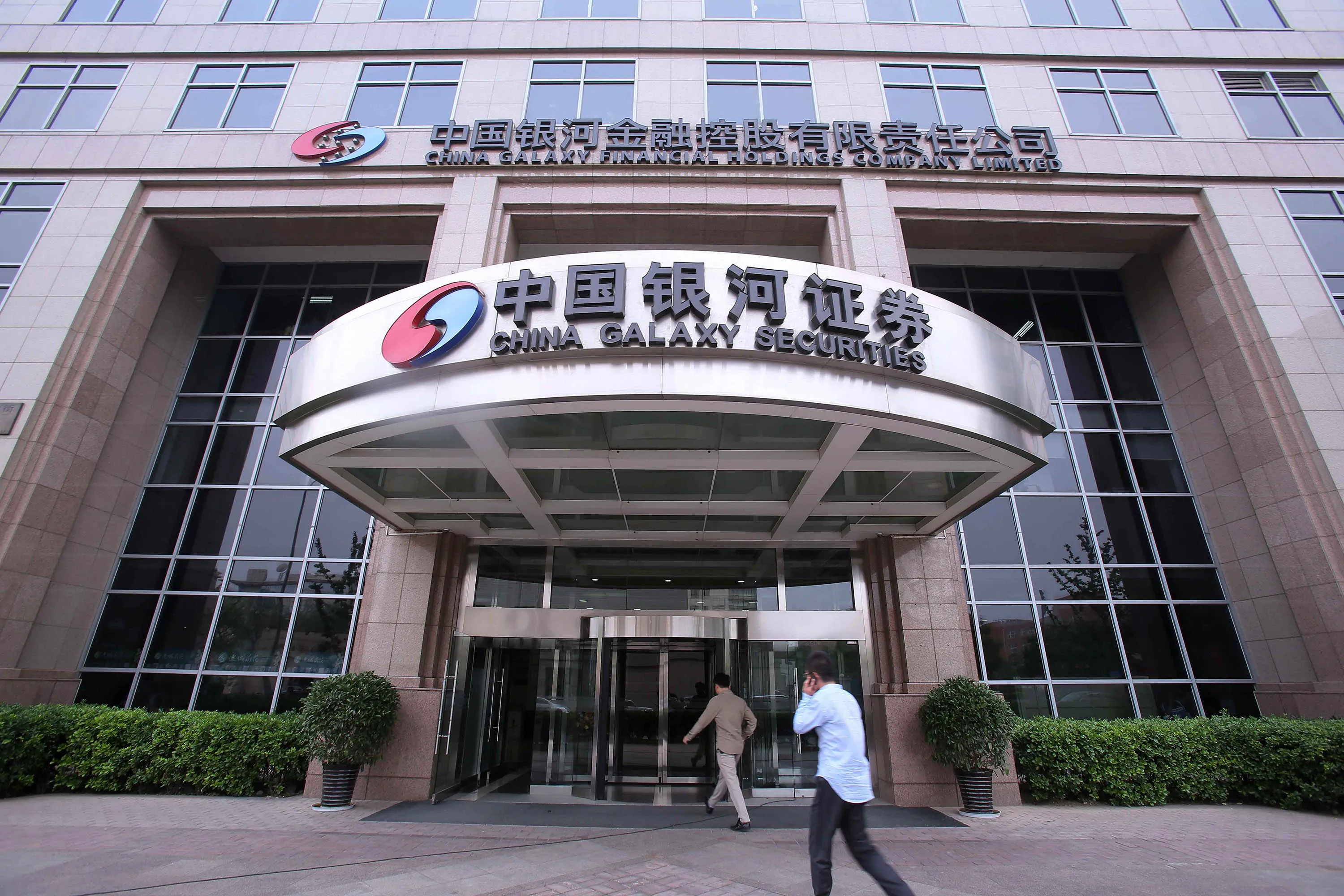 People walk into a China Galaxy Securities Co. office building in Beijing.