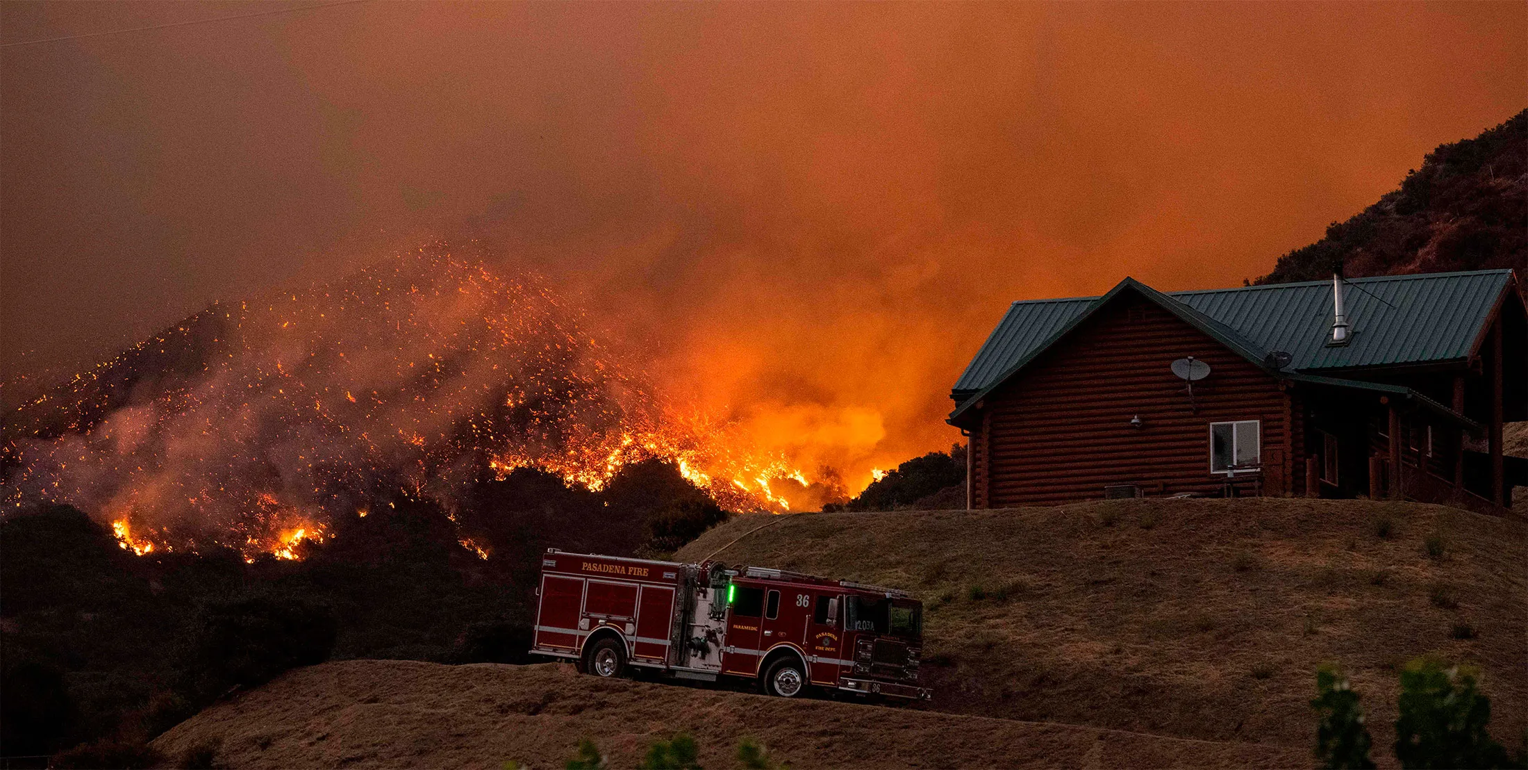 Pasadena Fire Department firefighters defend a home during the Apple fire in Banning, Calif., on Aug. 1, 2020.