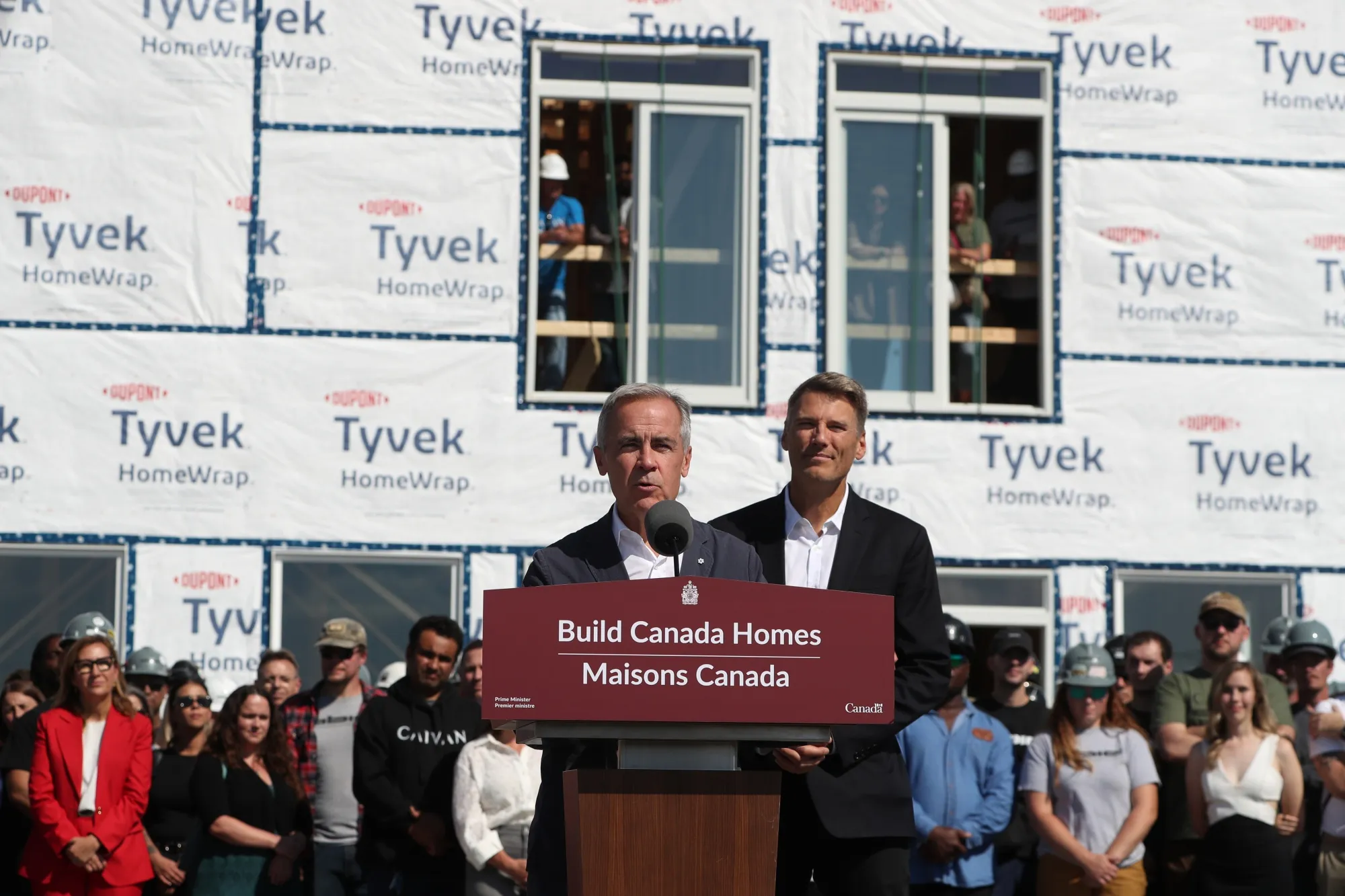 Mark Carney, center left, speaks during a news conference outside of a modular housing site in Ottawa on Sept. 14.