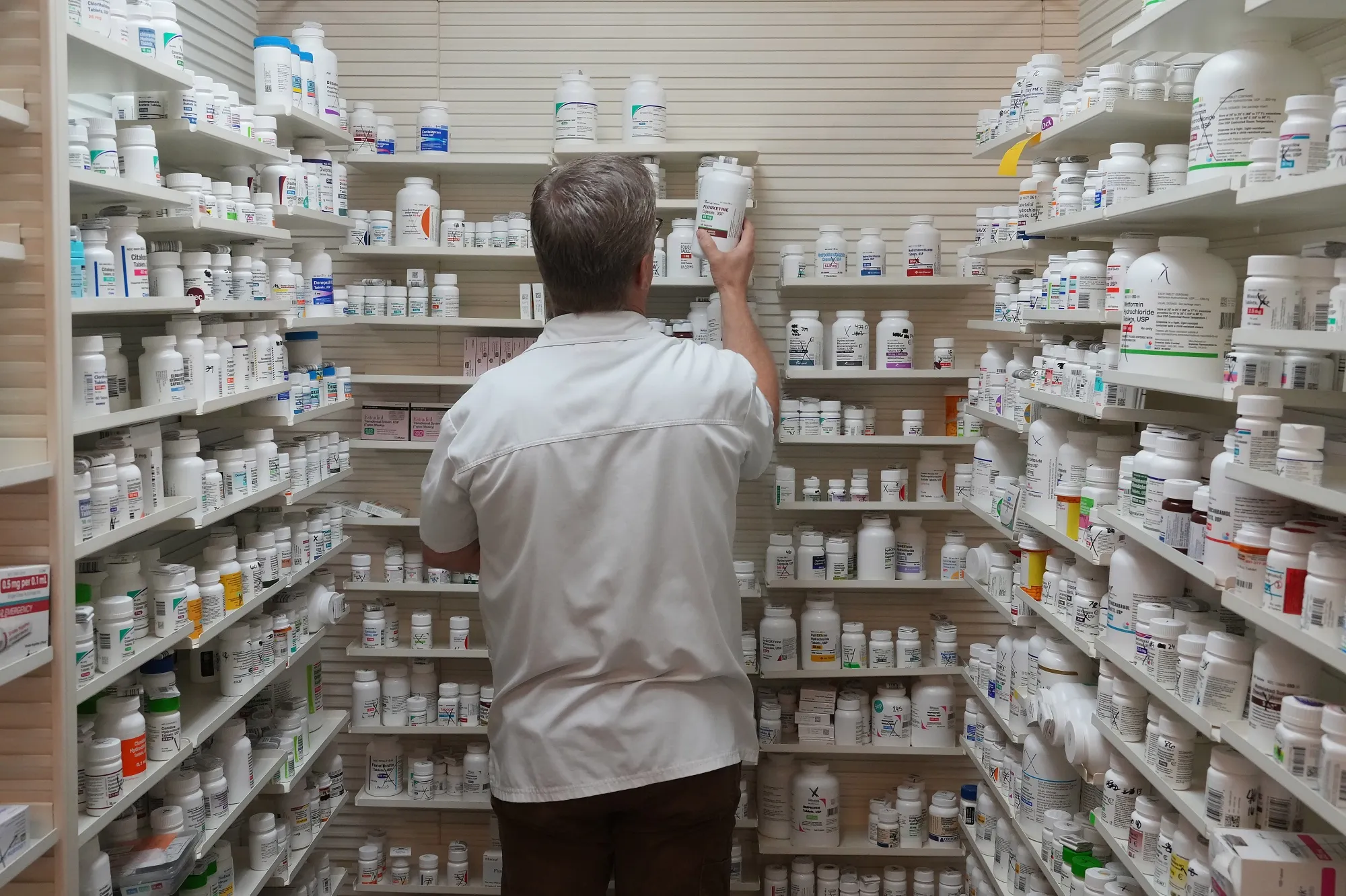 A pharmacist pulls a drug from a shelf inside a pharmacy in Provo, Utah.
