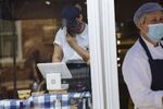 A worker wearing a protective mask uses a Square Inc. terminal inside a shop in Hudson, New York, U.S.