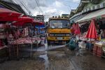 A sanitation worker uses a high-pressure water hose to wash down a market in Bangkok, on March 25.
