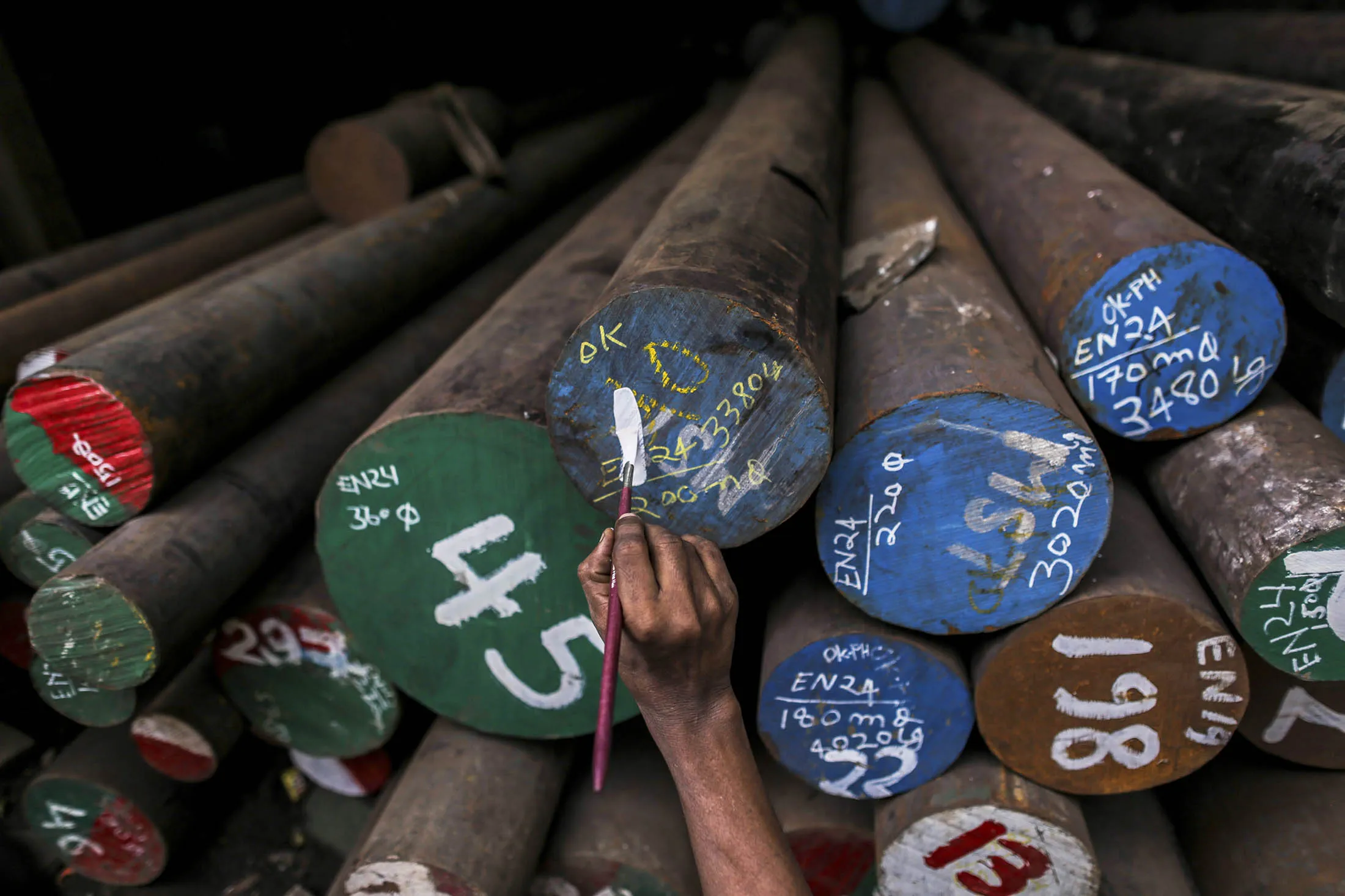 A worker writes on an iron beam at a wholesale steel and iron market in Mumbai, India.
