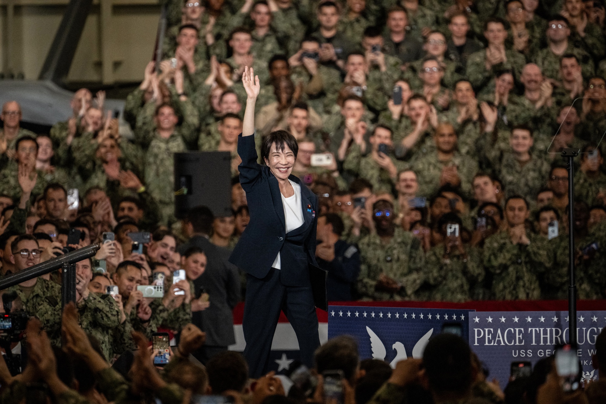 Japan's Prime Minister Sanae Takaichi gestures as she takes to the podium to speak in front of US Navy personnel during US President Donald Trump's visit to the USS George Washington aircraft carrier at the US naval base in Yokosuka on October 28, 2025. (Photo by Philip FONG / AFP) (Photo by PHILIP FONG/AFP via Getty Images)