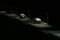 Dump trucks carrying boulders make their way over the Oroville Dam in the night on Feb. 13, 2017.