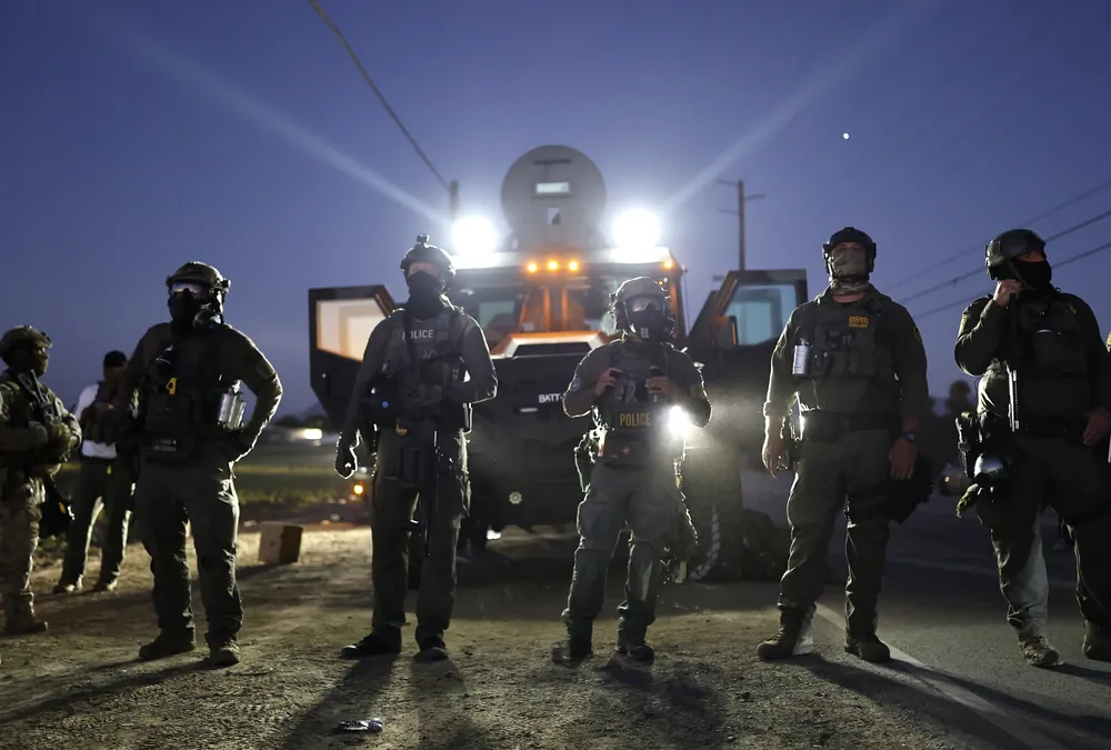 CAMARILLO, CALIFORNIA - JULY 10: Federal agents block people protesting an ICE immigration raid at a nearby licensed cannabis farm on July 10, 2025 near Camarillo, California.