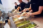 Employees prepare food items including a Chipotle Mexican Grill burrito bowl.
