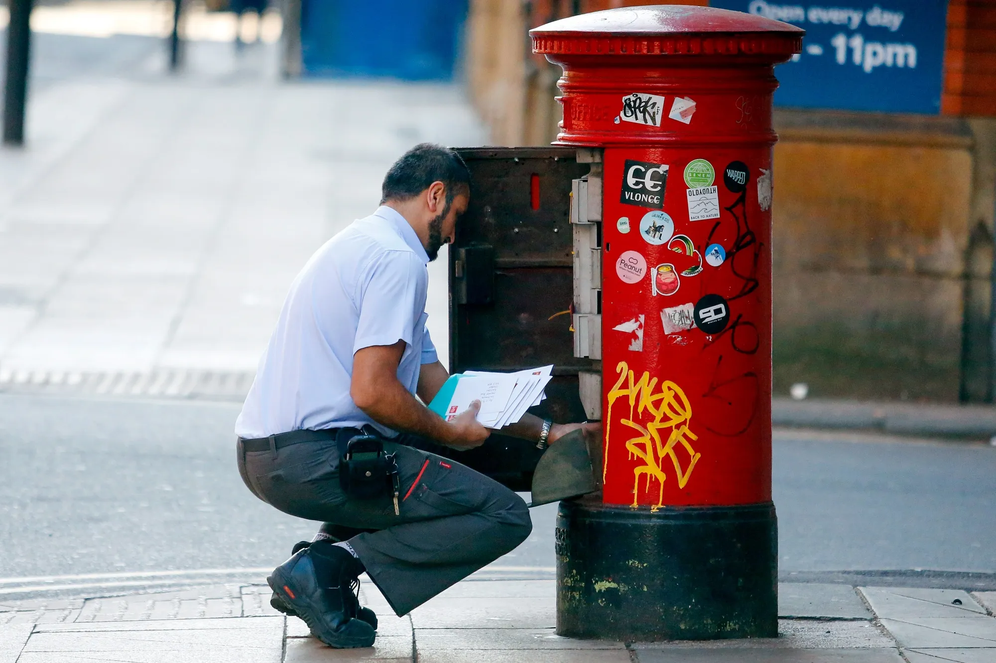 A postal worker for Royal Mail Plc empties a postbox in Manchester.