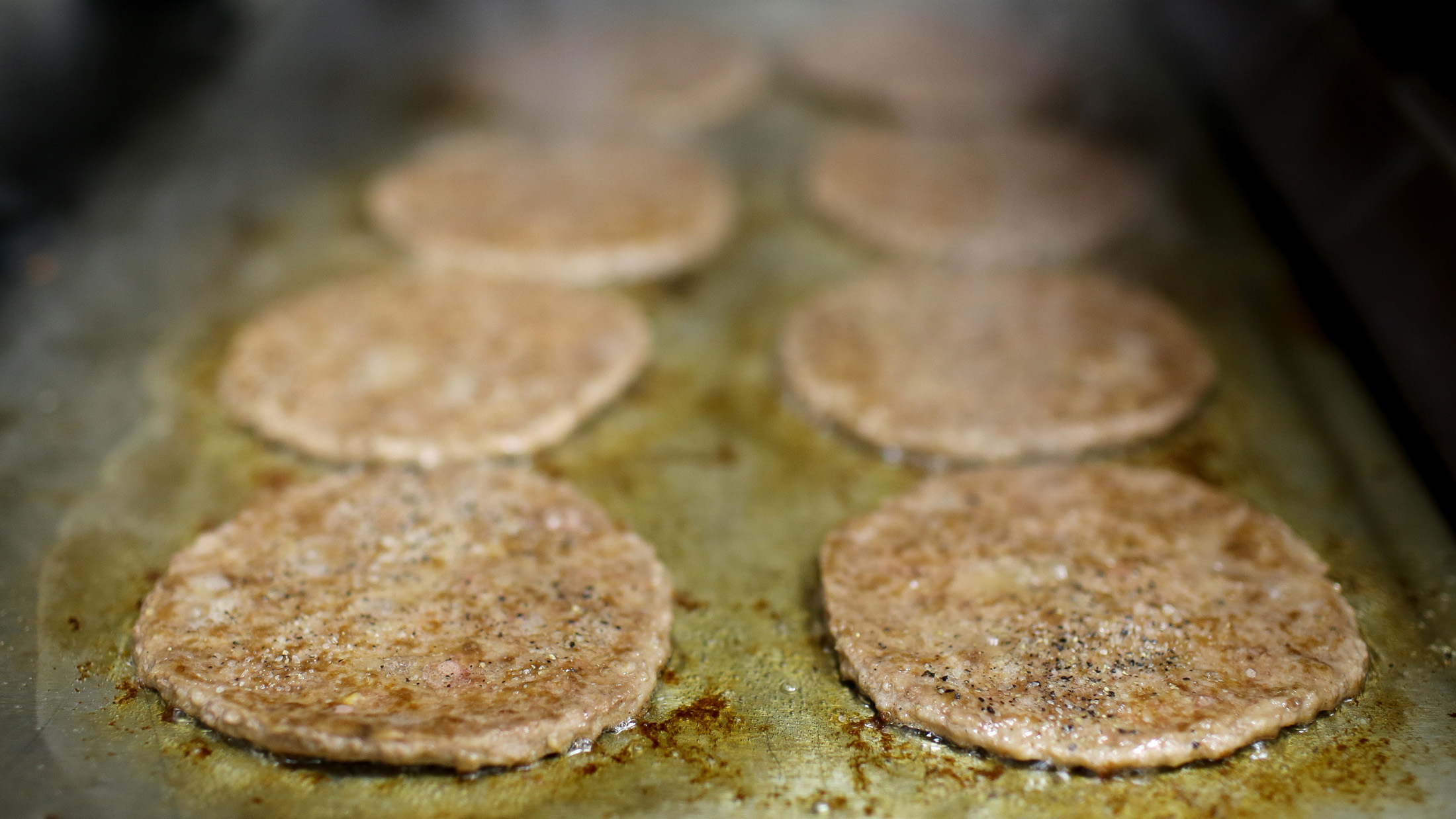 Burger patties cook in the kitchen of McDonald's restaurant.
