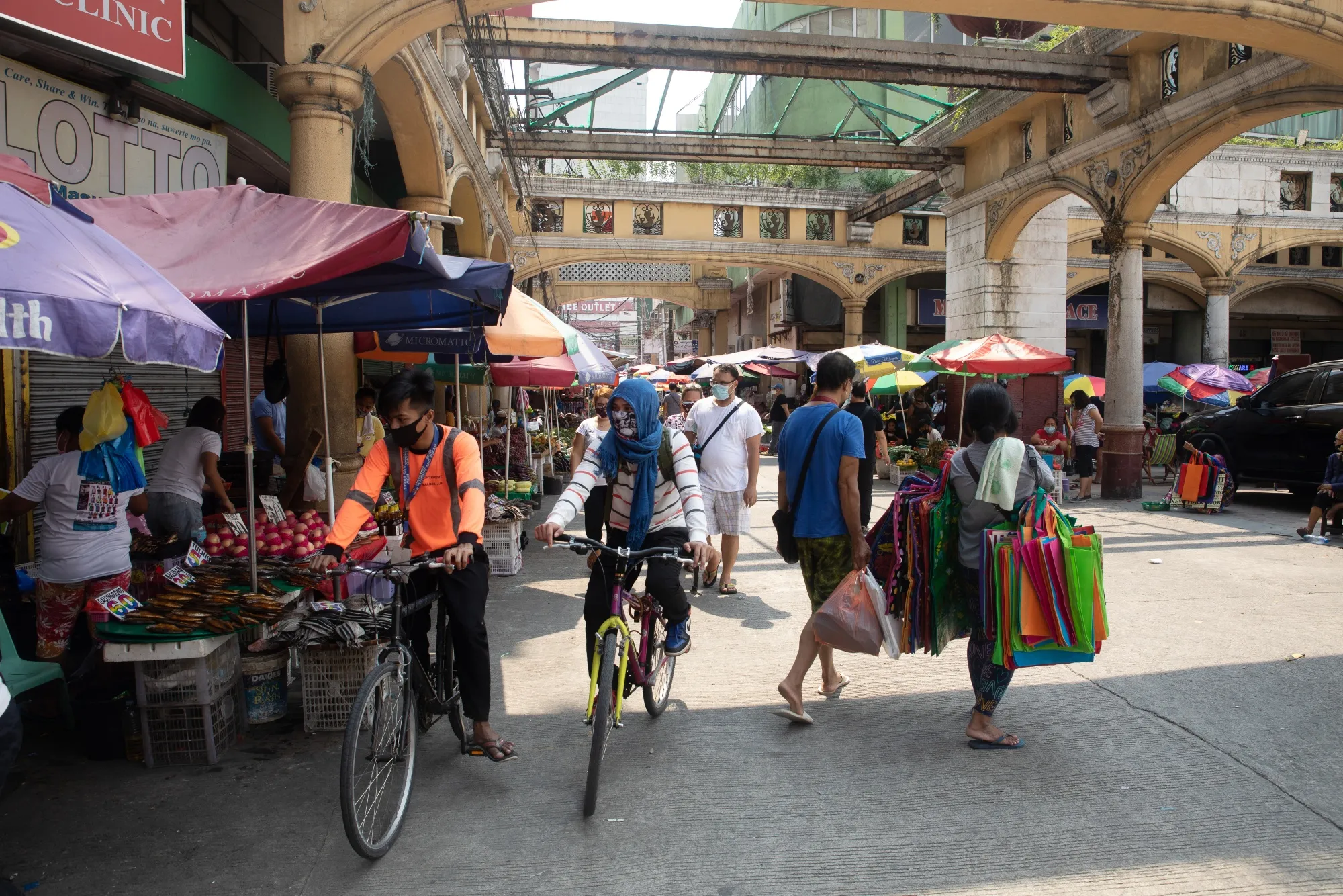 Cyclists wearing protective masks ride past stores and shoppers at Quiapo Market in Manila, the Philippines, on&nbsp;July 27.