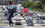 A woman crosses an overpass above the 101 freeway in Los Angeles, California.