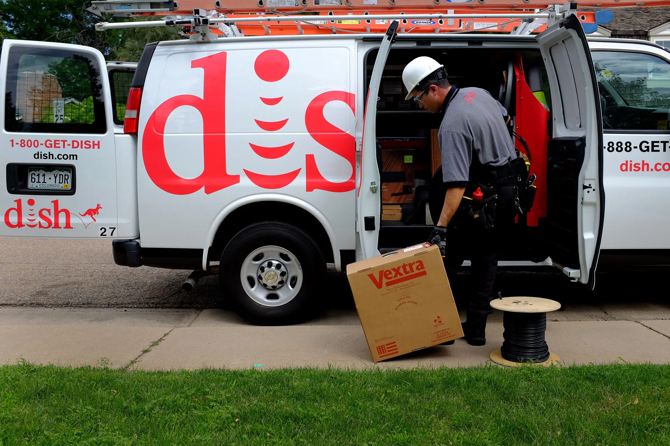 Justin Preziosi, field service specialist for Dish Network Corp., prepares to install a satellite television system at a residence in Denver, Colorado, U.S., on Tuesday, Aug. 6, 2013. Dish Network Corp., the third-largest U.S. pay-TV company by customers, and Charter Communications Inc., the eighth-biggest, both may look to combine with competitors as a way to gain leverage in negotiations with TV networks to carry their programming.
