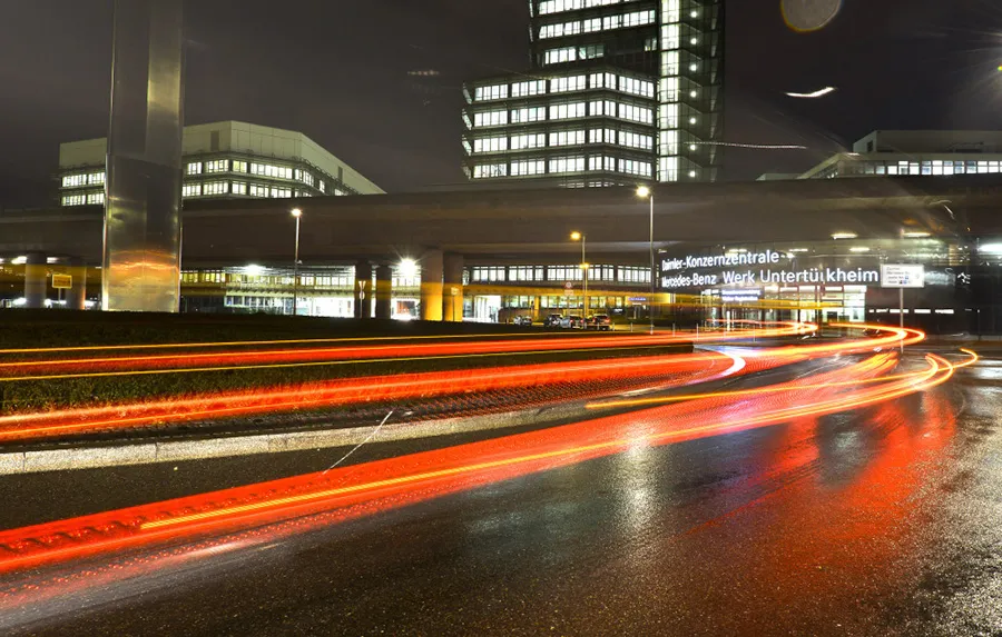 Taillights from passing traffic illuminates the road near the entrance of the Daimler headquarters in Stuttgart.
