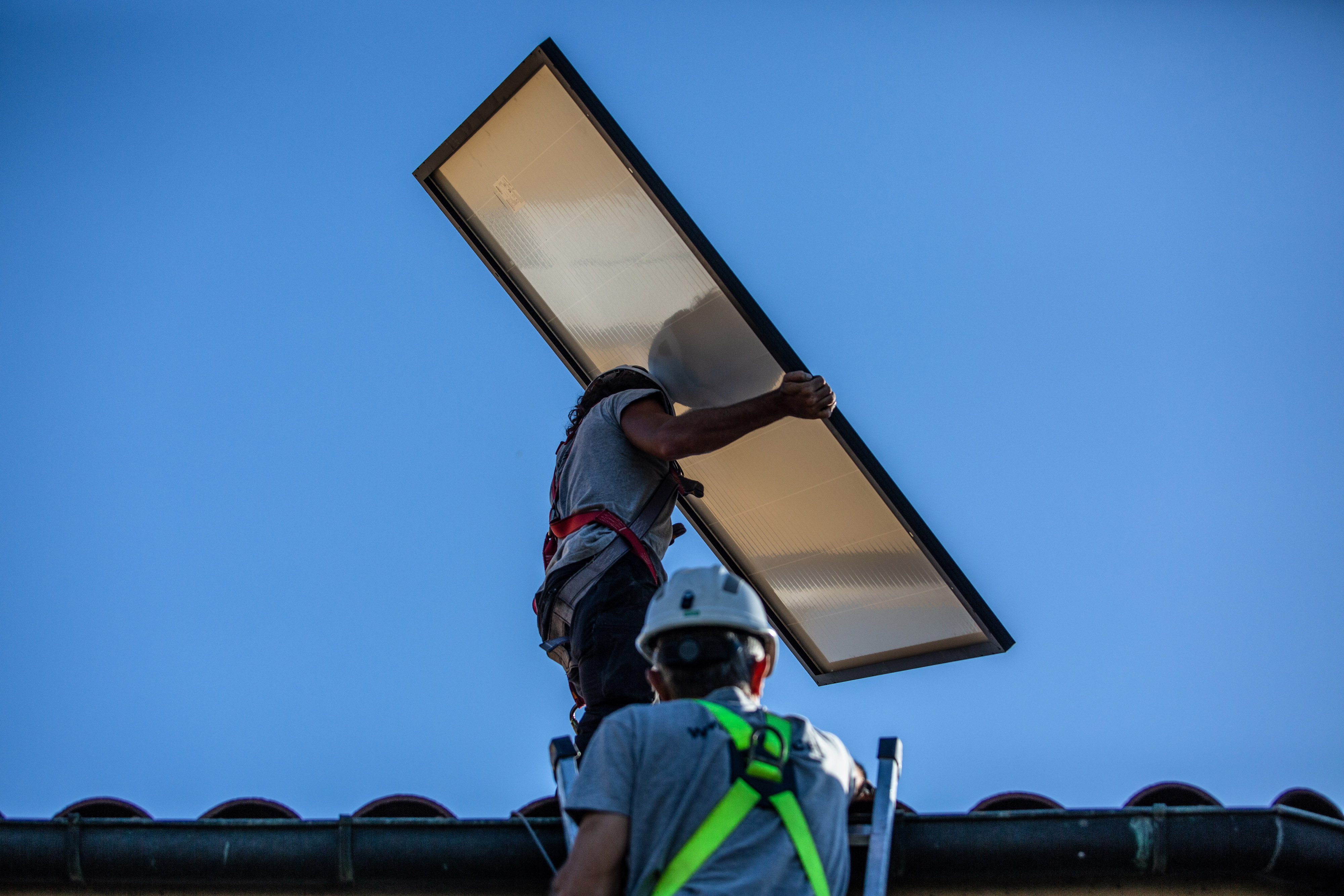 Engineers install solar panels onto a roof of a property in Barcelona.