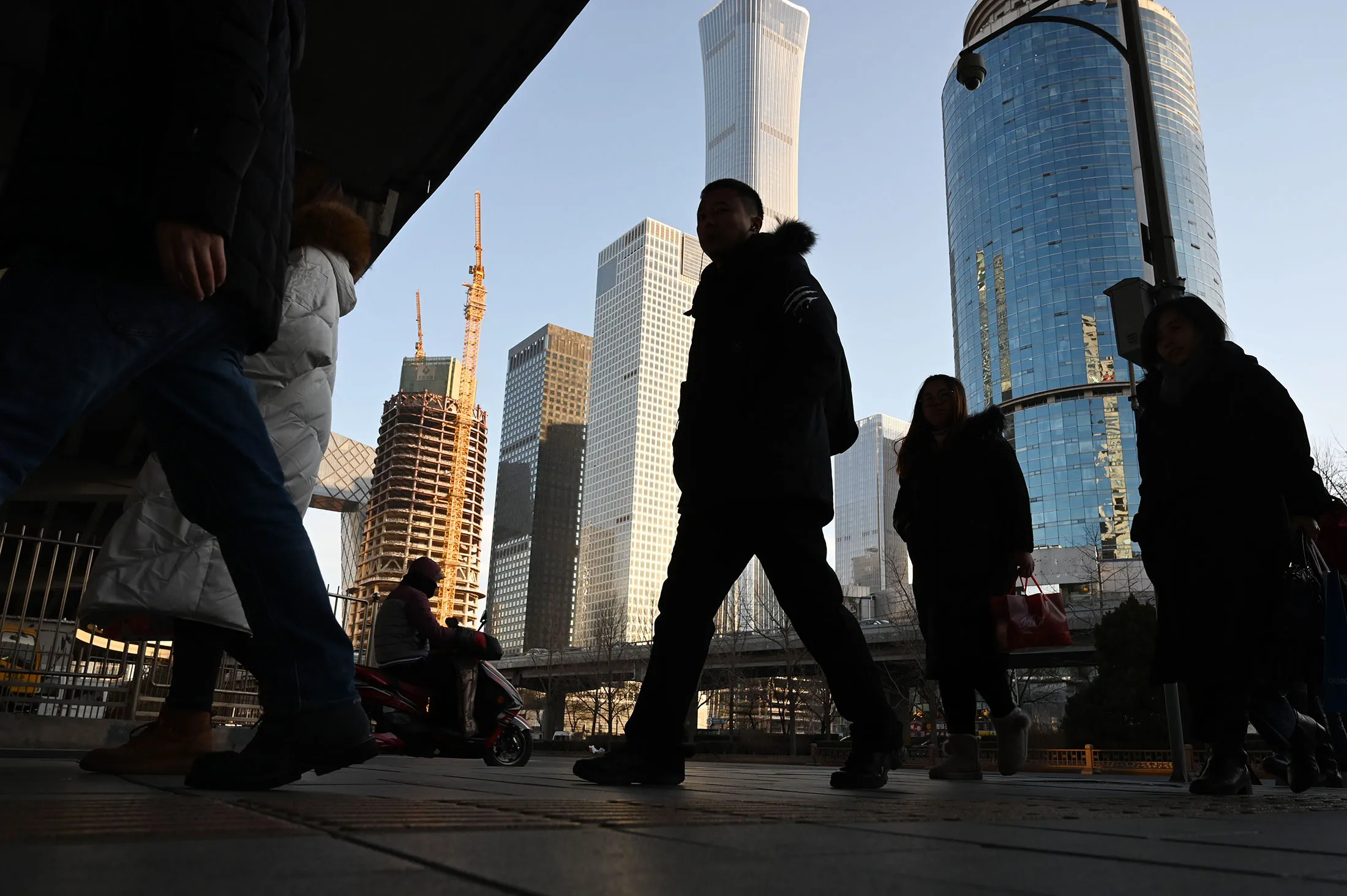 Commuters cross a road in the central business district of Beijing, on Jan. 21.