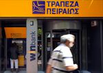A Piraeus Bank SA customer uses an automatic teller machine (ATM) which stands outside a company branch in Athens.
