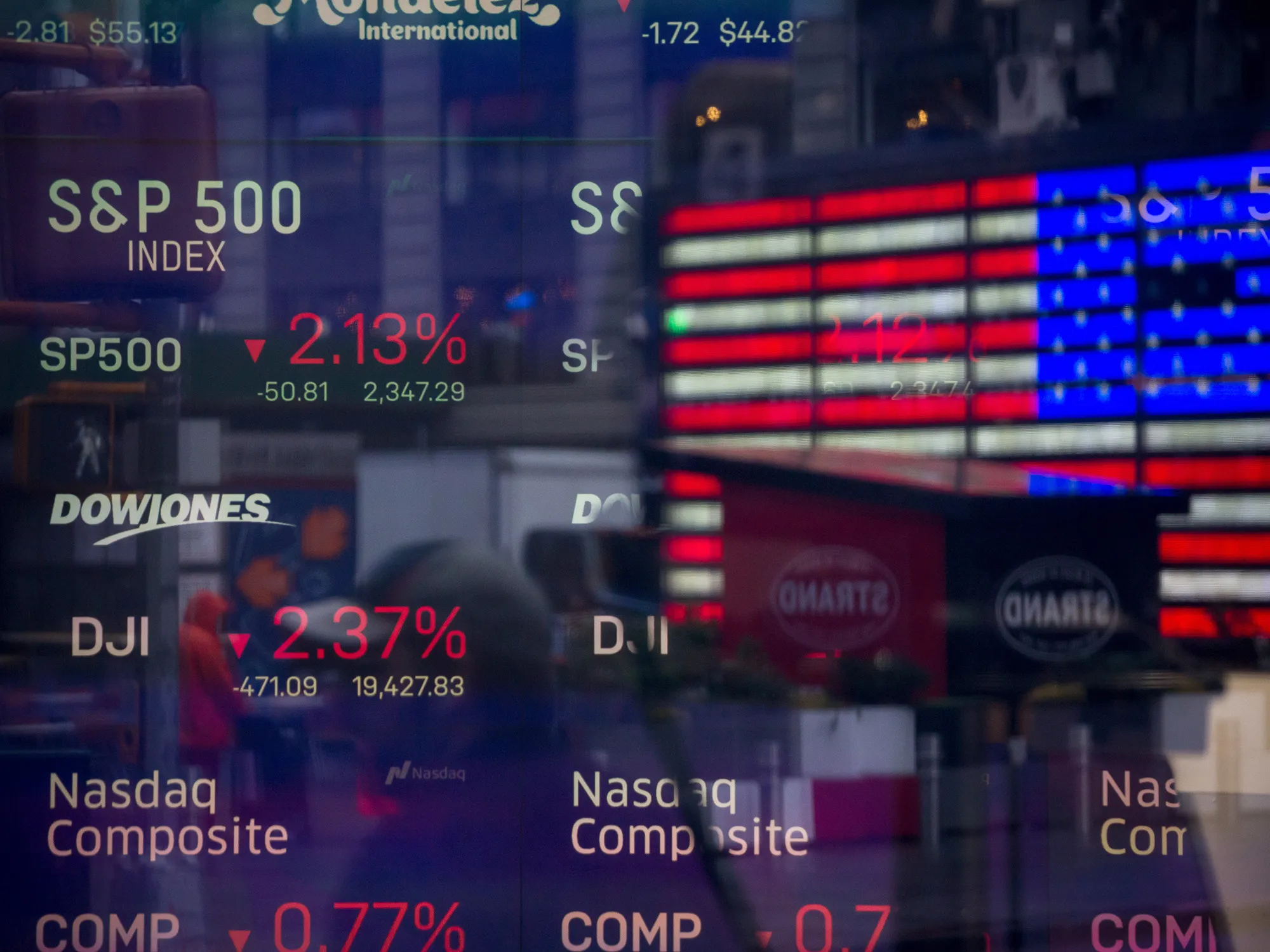 Monitors displaying stock market information are seen through the window of the Nasdaq MarketSite.
