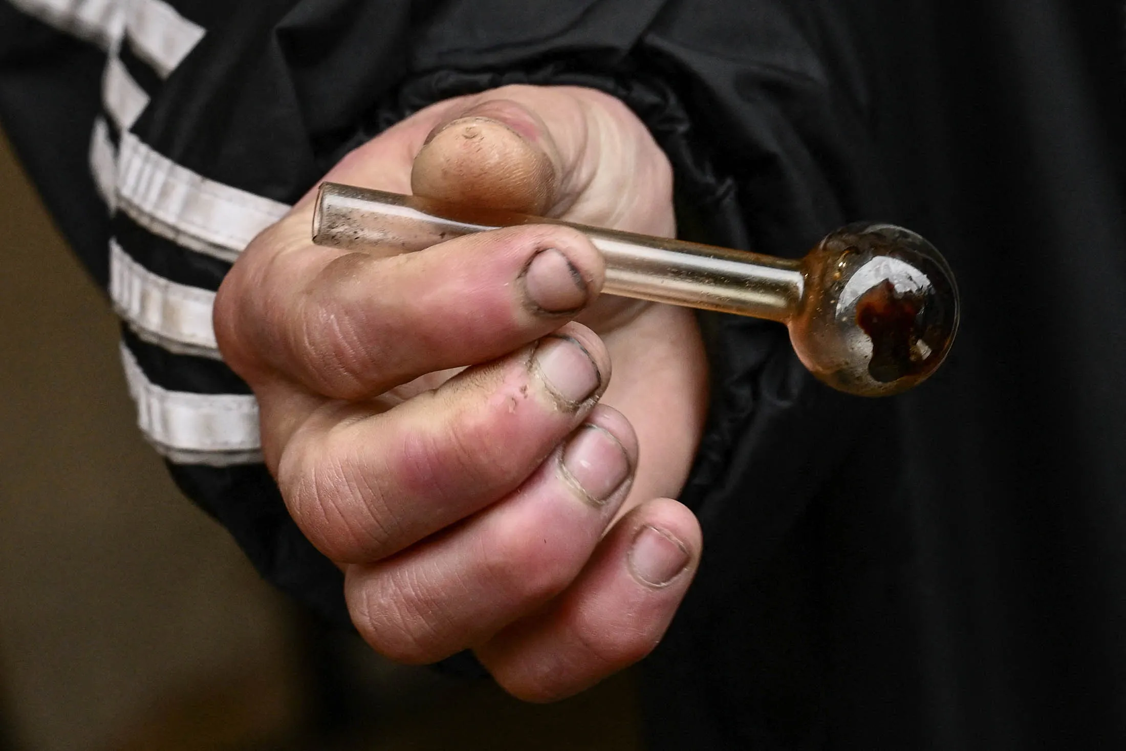 A person holds a glass pipe used to smoke meth in downtown Portland, Oregon.