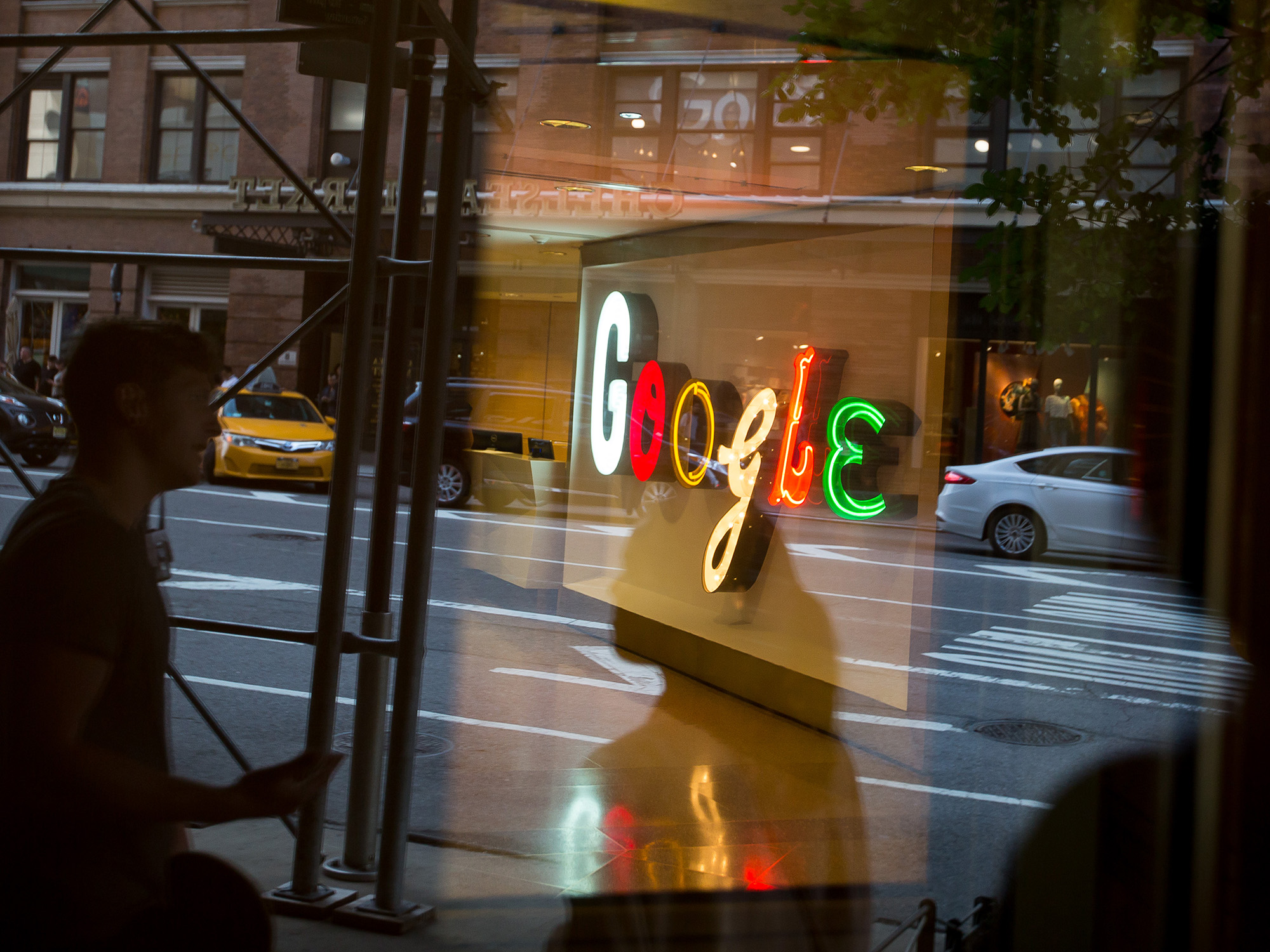 Pedestrians are reflected in a window looking into a lobby of the Google Inc. offices in New York.