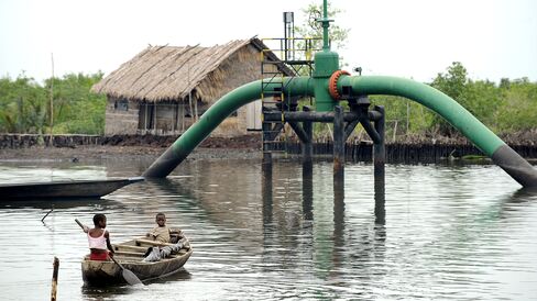 Children sail past an oil pipeline head