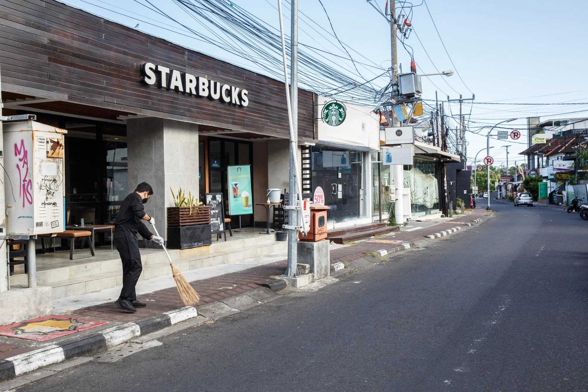 An employee sweeps outside a Starbucks restaurant in Bali on May 12.