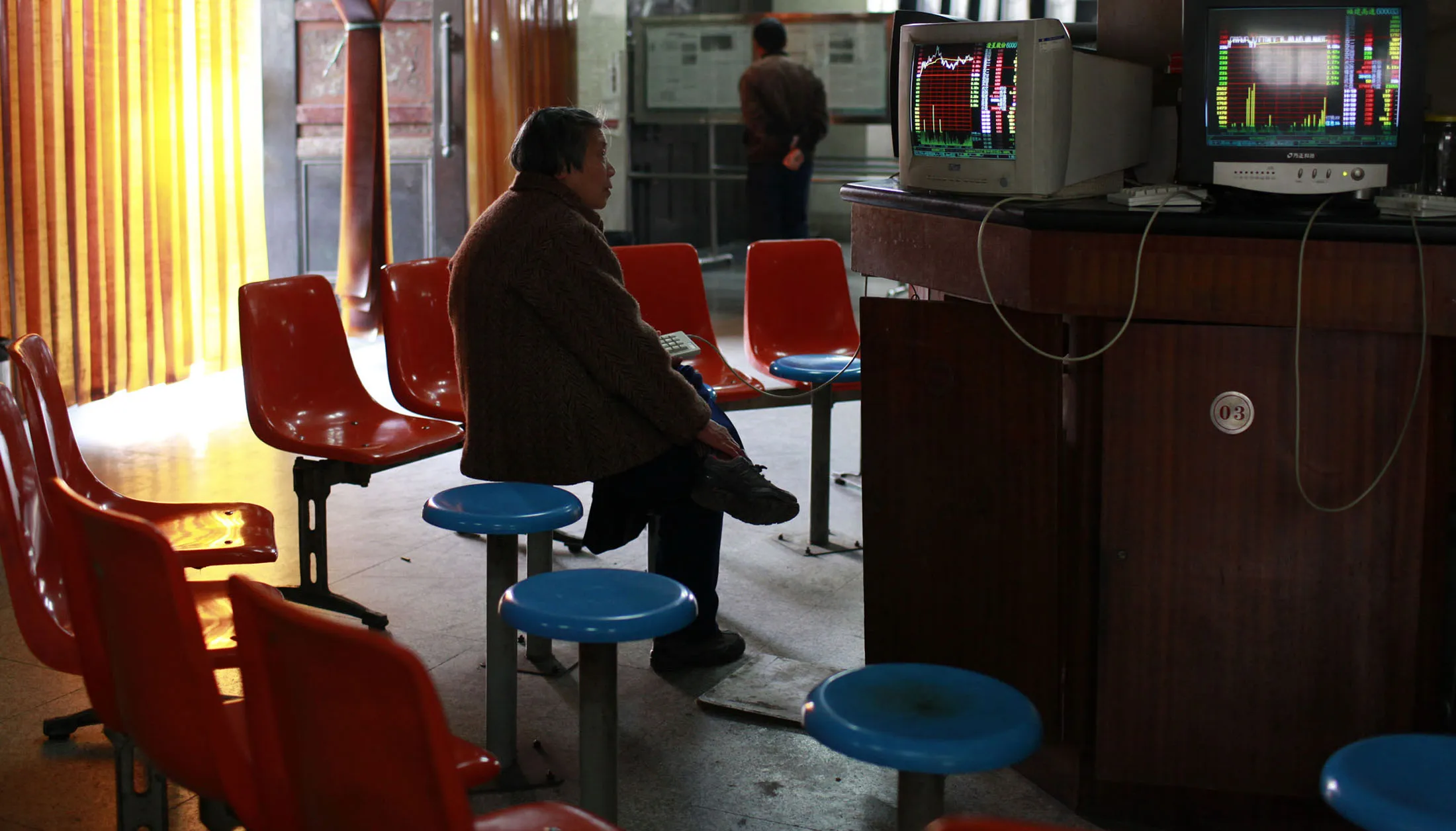 A woman monitors prices at a securities exchange hall in Shanghai.
