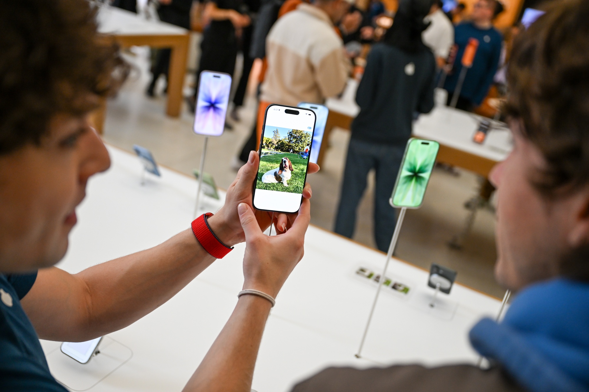 An Apple retail employee shows a customer the Photos app on an iPhone Air.