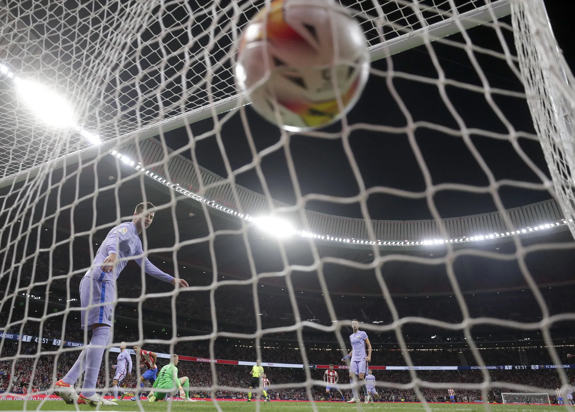 Barcelona's Gerard Pique looks round as Atletico Madrid's Luis Suarez, center rear, celebrates after scoring his side's second goal during the La Liga soccer match between Atletico Madrid and Barcelona at the Estadio Wanda Metropolitano in Madrid, Saturday, Oct. 2, 2021. (AP Photo/Manu Fernandez)