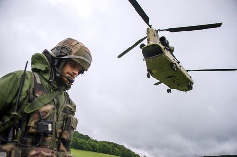 Chinook helicopter passes over a French soldier during a French-US 'Royal Blackhawk' military exercise with French, US, Dutch, British and Belgian troops, on May 20, 2015, in Baume-Les-Dames, eastern France.