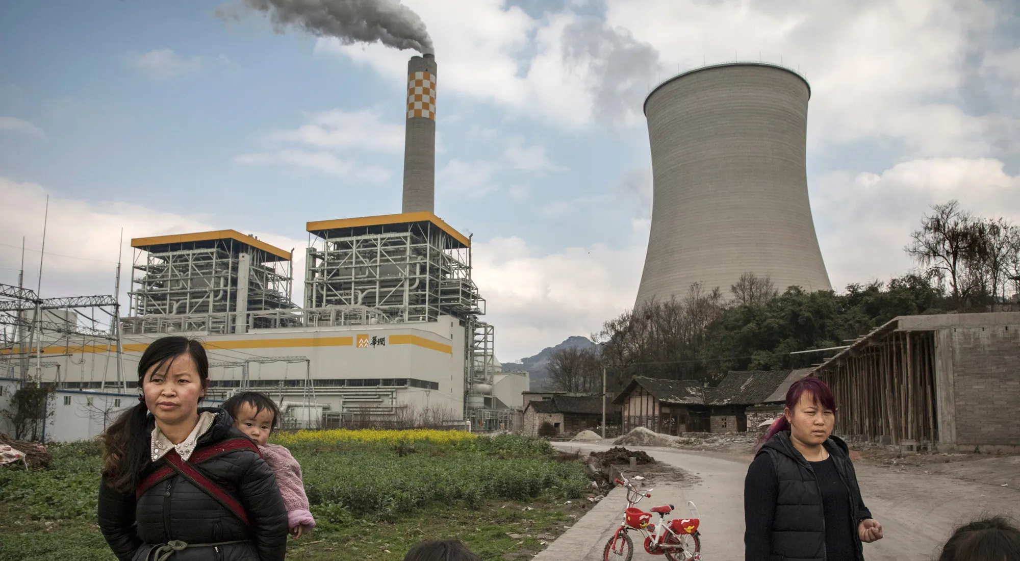 Chinese villagers stand near a newly built state-owned coal fired power plant in Guizhou.