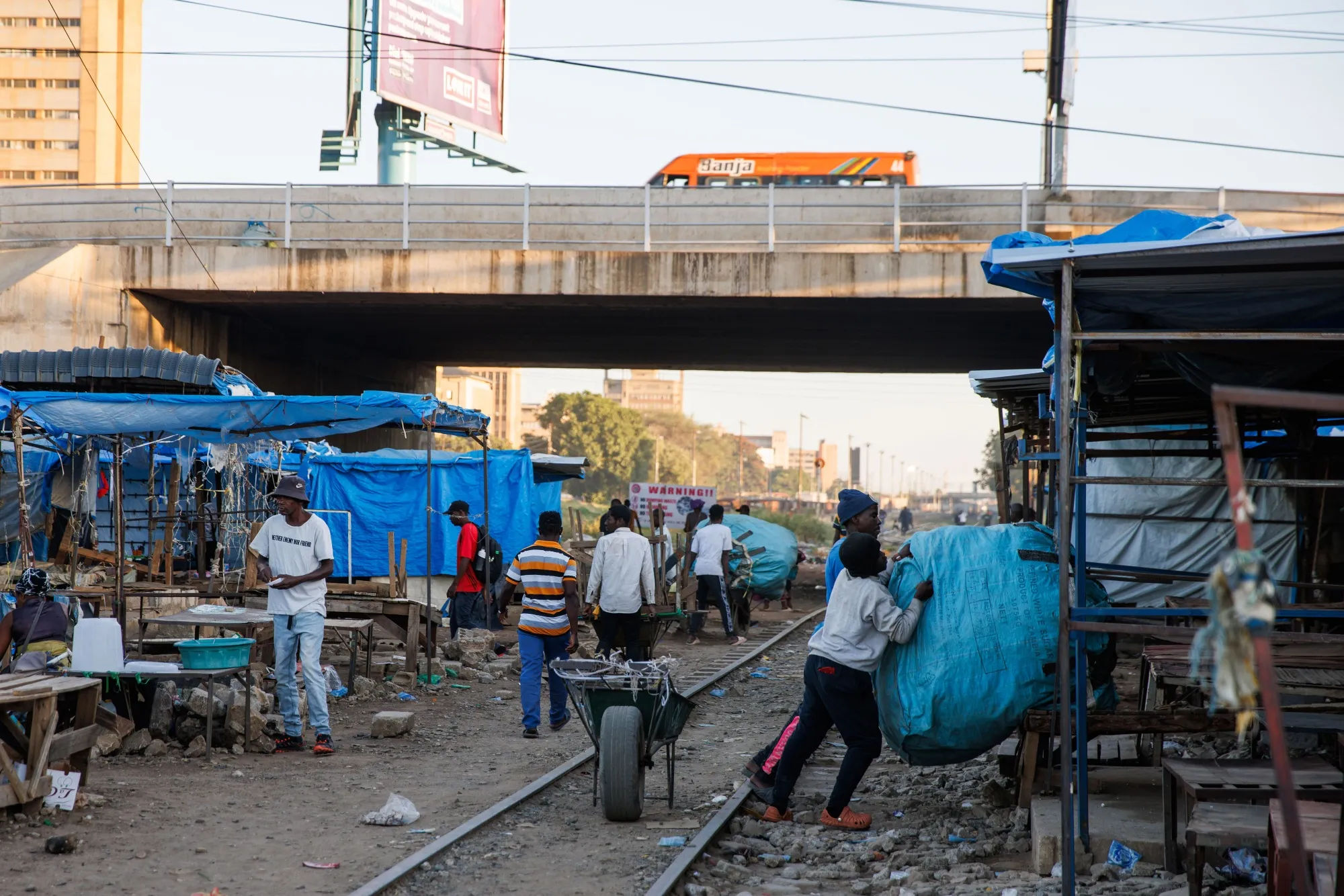 Traders transport bundles of secondhand clothing at a street market area in Lusaka, Zambia.